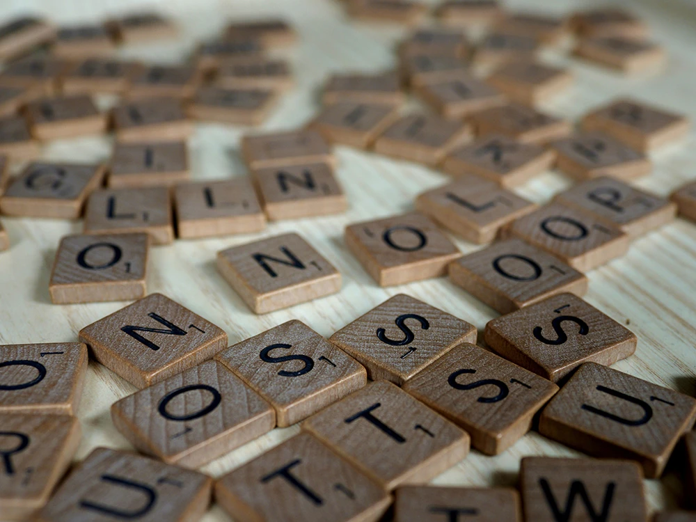 Scrabble tiles scattered across a wooden surface, symbolising the challenge of learning how to process your emotions.