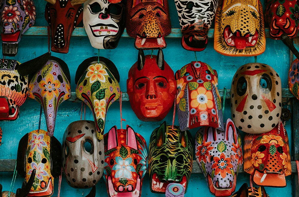 A colourful wall display of traditional masks symbolising the hidden dangers of falling in love with the wrong person.