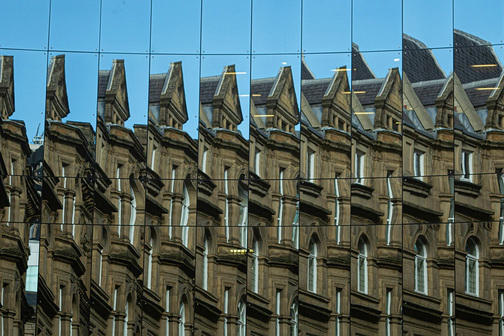 Fragmented reflection of a historic building in mirrored panels, creating a repeated pattern suggestive of repetition compulsion.