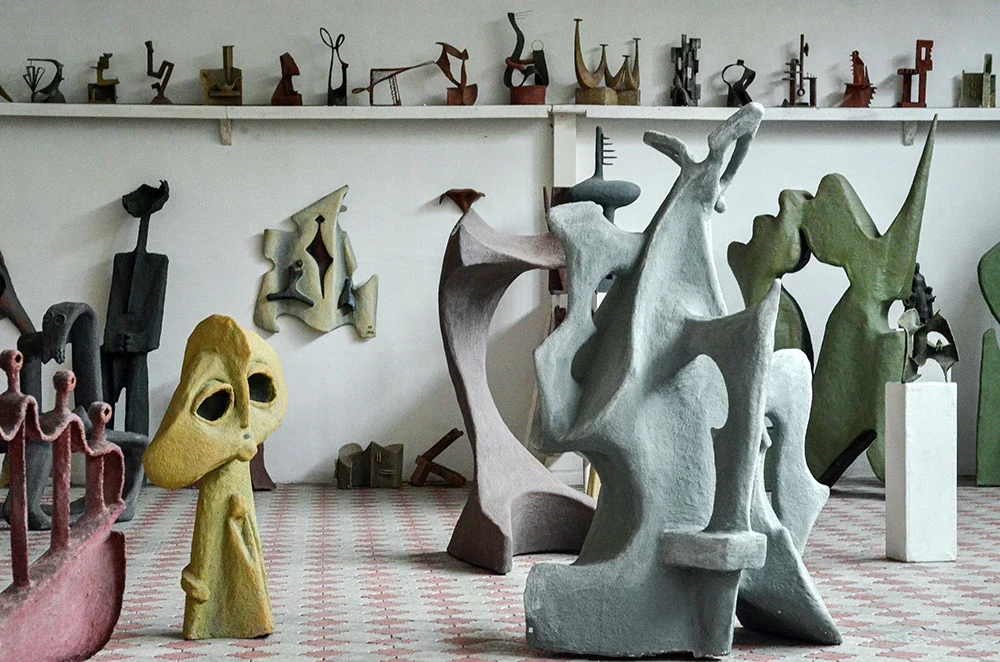 An artist’s studio filled with large abstract sculptures in muted colours.